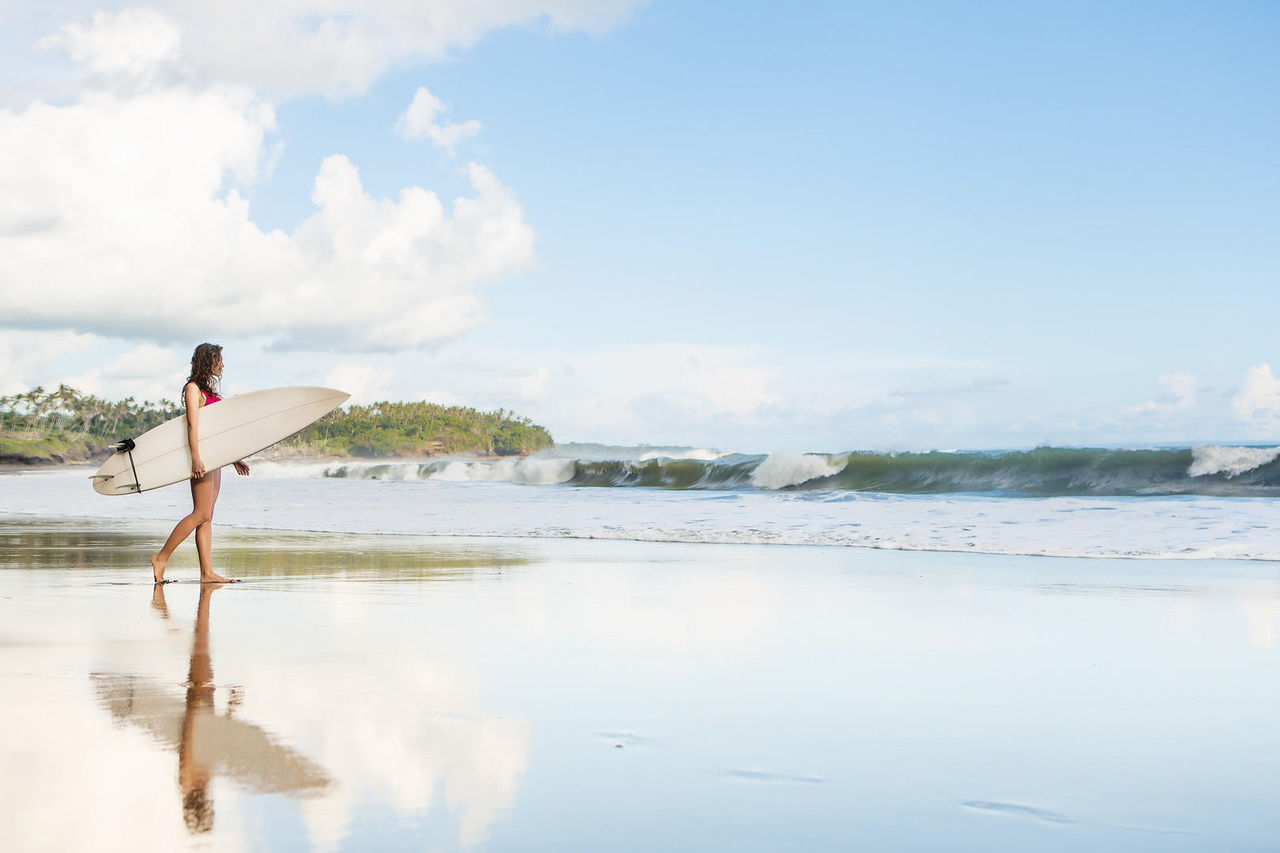Beach Walking Young lady with surfboard going to the ocean at surf spot